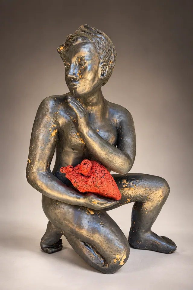 Kneeling dark figure holding a red heart