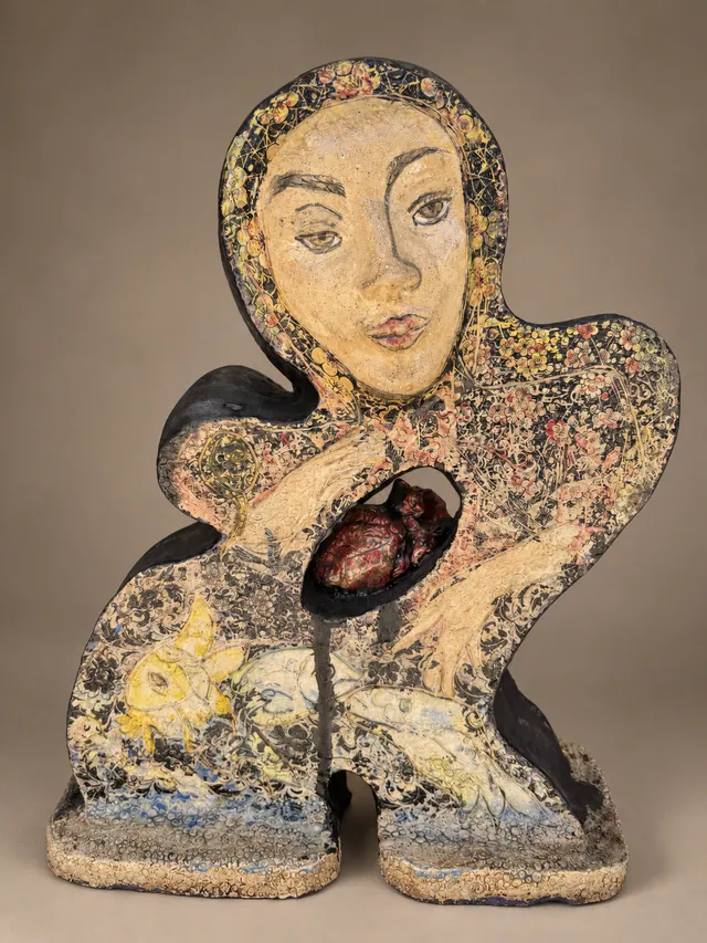 Figure-shaped slab with a woman's face and a heart in an open window
