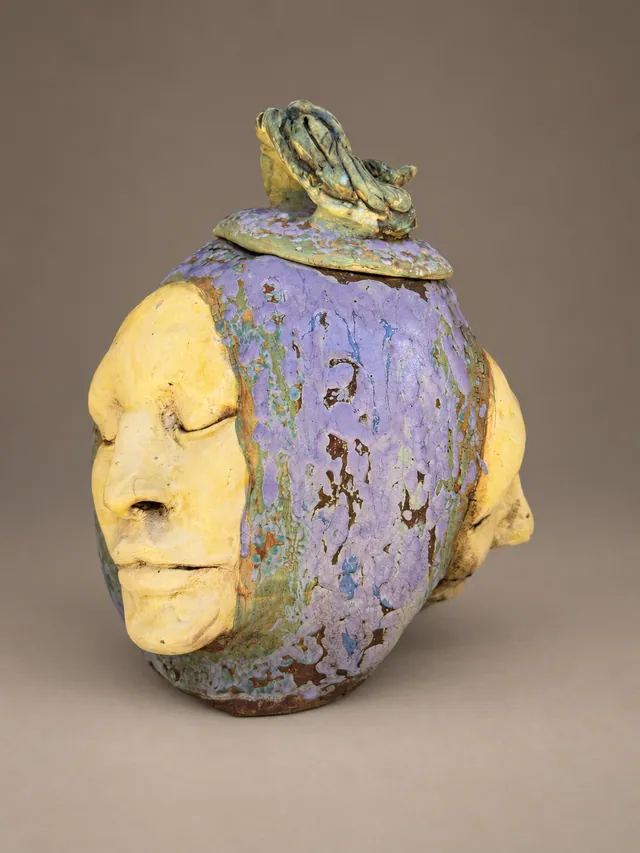 Lavender lidded vessel with faces and a lizard on the lid