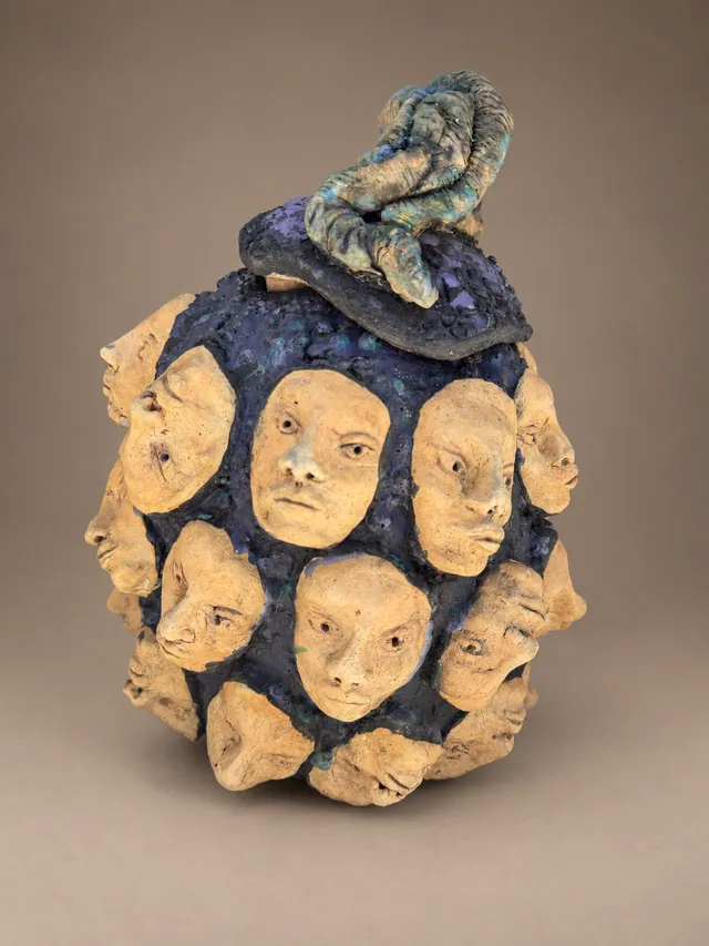 Lidded vessel covered in small faces