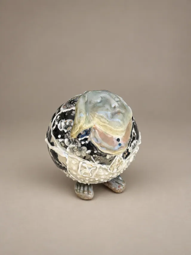 Round figure on small feet in black and white glaze