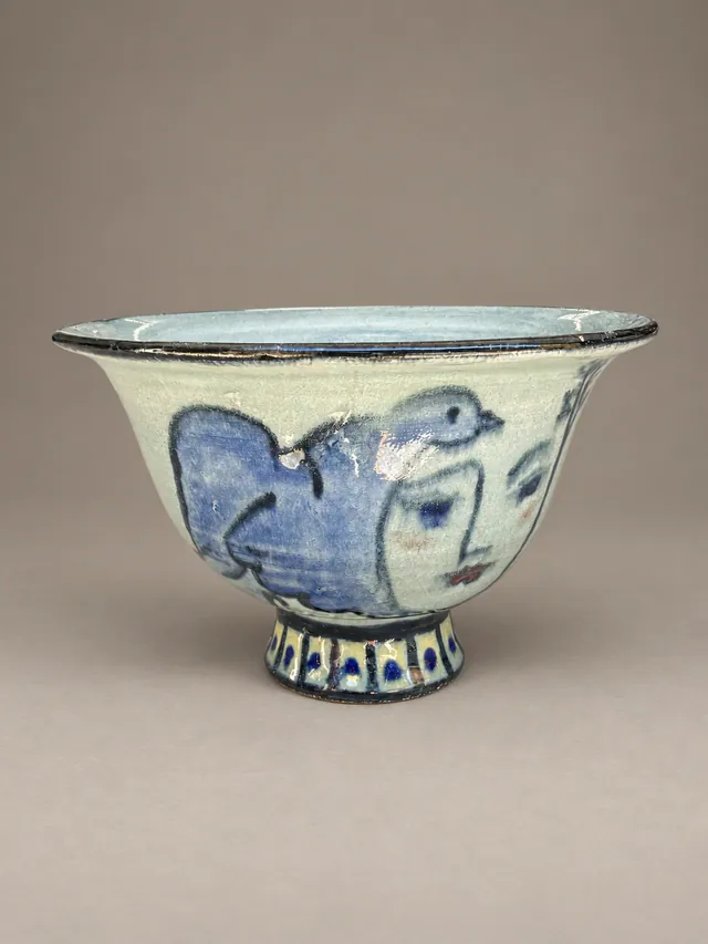 Footed bowl painted with a face and a bird in blue