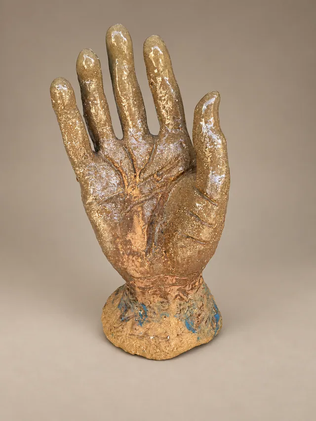 Amber-glazed hand with a face in the palm