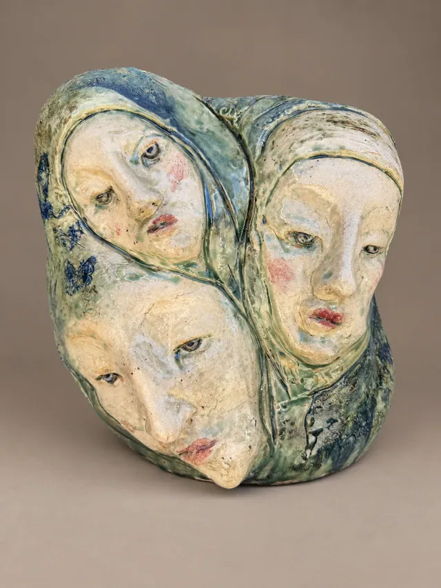 Three faces in pale glazes, clustered together